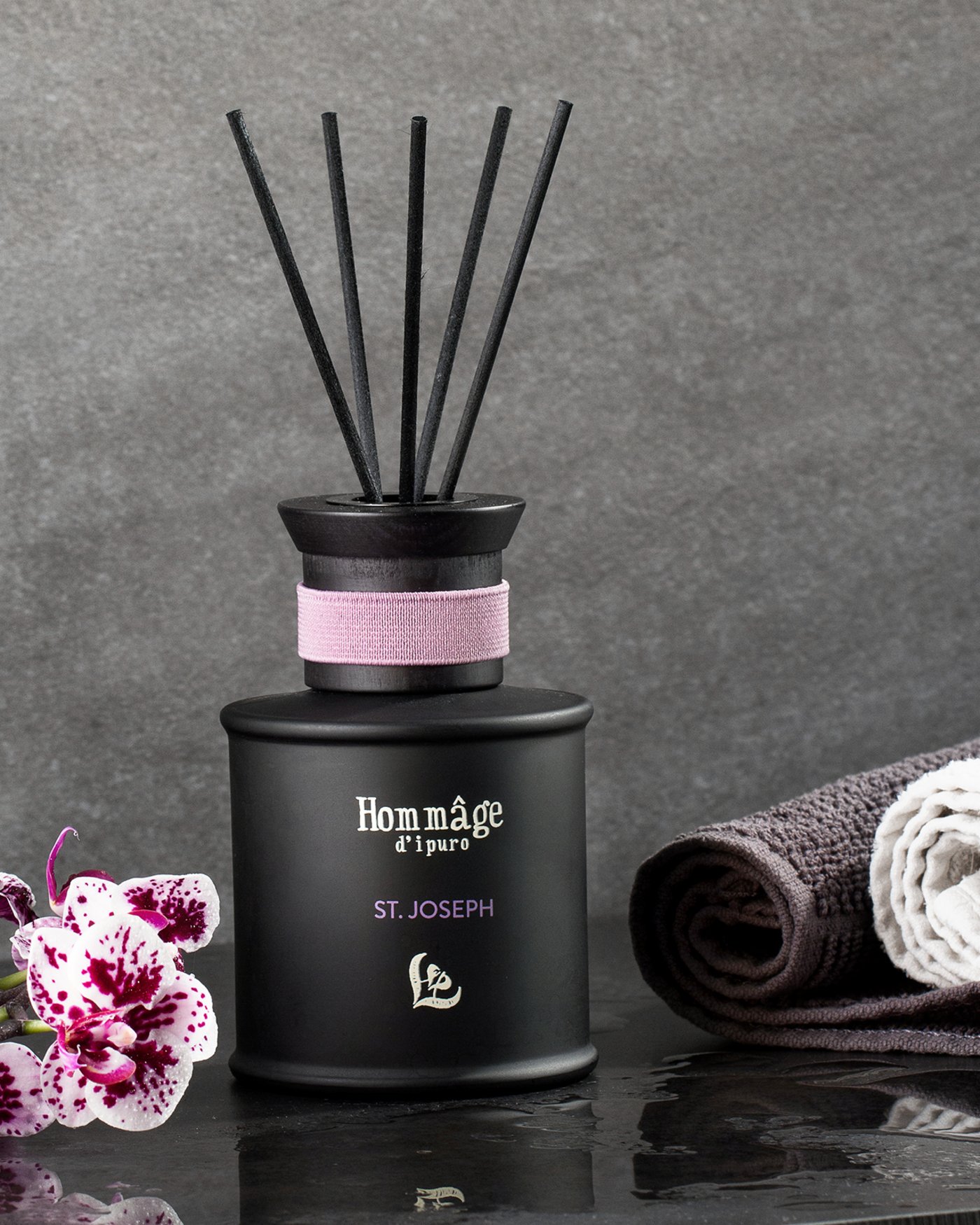 Werbliche Produktaufnahme als Stilleben von einem Duftflacon mit Orchidee und Handtüchern